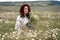 Chamomile woman. Happy curly woman in a chamomile field, dressed in a white dress.