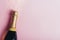 Champagne bottle with gold ribbon on pastel pink background with glitter. New year celebration banner design. Minimal flat lay