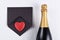 Champagne bottle with a red heart on a black envelope
