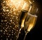 Champagne flutes with golden bubbles on dark golden light bokeh background