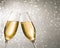 Champagne flutes with golden bubbles on silver light bokeh background