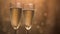 Champagne glasses over holiday bokeh blinking background, rotating on turntable, glasses with sparkling wine