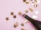 Champagne glitter and star shaped gold confetti on the pink background