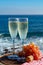 Champagne, prosecco or cava served with pink grape in two glasses on outside terrace with sea view