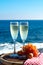 Champagne, prosecco or cava served with pink grape in two glasses on outside terrace with sea view