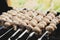 Champignon mushrooms on metal skewers are cooked on charcoal