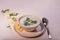 Champignon puree soup on a plain beige table. Nearby is a tablespoon and scattered delicacy crackers