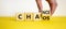 Chance or chaos symbol. Businessman turns a cube and changes the word `chaos` to `chance`. Beautiful yellow table, white