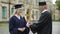 Chancellor of university giving diploma to student, shaking hand, commencement