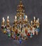 The chandelier is gold in color, with light bulbs in the form of a candle. Crystal pendants, colored glass pendants