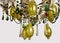 The chandelier is gold in color, with light bulbs in the form of a candle. Crystal pendants, colored glass pendants