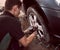 Changing car wheel and tyre in auto repair service. Focus on professional mechanic hands with pneumatic wrench in action