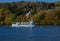 The changing colours of autumn trees & a Pleasure Cruiser. Windermere. Lake District, UK