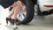 Changing wheels indoors, woman changing car tyres, girl rolling spare wheel for tire replacement