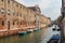 Channel with boats and historic buildings on embankment. Venice, Italy