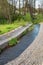 A channel made of granite stones for the river stream with grass and shrubs on the banks. Landscaping of the city, river