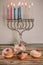 Chanukah celebration concept. Close up view of tasty donuts with jam and menorah traditional candelabra.