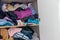 Chaotic wardrobe and sloppy closet shows many outfits of a woman with shopping addiction and many clothes like pullovers, shirts a