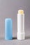 Chapstick open tube over gray background. Moisturizing lip balm for dry lips macro. Colorless protective lipstick for winter