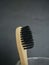 Charcoal infused bamboo toothbrush in glass on grey black background. Vertical.