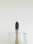 Charcoal infused bamboo toothbrush in glass with off white background