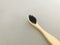 Charcoal infused bamboo toothbrush on grey texture background.