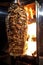 Charcoal shawarma meat. Closeup of chicken meat collected on a vertical skewer and grilled on charcoal.