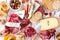 Charcuterie board of assorted cheeses, meats and appetizers, top view table scene over white wood