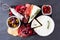 Charcuterie platter of assorted meats, cheeses and appetizers on a dark slate background