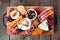 Charcuterie tray of a variety of meats, cheeses and appetizers over dark wood