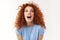 Charismatic beautiful redhead woman with curly hairstyle, making surprising and amused expression, widen eyes astonished