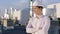 Charismatic businessman posing in front of the camera on the top of construction site he wearing safety helmet he