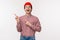 Charismatic funny young man in glasses and red beanie introduce something awesome, laughing and smiling excited pointing