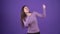 The charismatic girl looks forward gracefully and performs cheerful dance moves. Brunette isolated on a purple