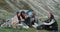 Charismatic group of teens have a picnic time , in the middle of mountain , sitting at campfire and drinking some wine