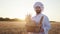 Charismatic man baker in the middle of the wheat holding a big basket of a fresh bread and smiling cute in front of the