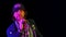 Charismatic musician sings into a microphone in a dark studio on a black background in the light of neon lights. The