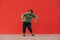 Charismatic positive fat man in casual clothes dancing on a red wall background. An overweight guy shows a dance performance on