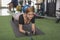 A charismatic woman smiles while doing planks on a black mat. Having fun and a lighthearted moment at the gym