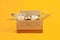 Charity concept. Open donation cardboard box with various food on a yellow background