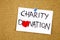 charity donation phrase handwritten on sticky note pinned to a cork notice heart symbol instead of O