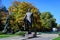 Charles de Gaulle statue and large green and yellow trees at the entry in Herastrau Park in Bucharest, Romania, in a sunny autumn