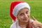 Charming 8 years old girl in santa claus hat raises a finger up and smiles. Christmas. New year concept. copy space