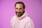 Charming alluring handsome bearded stylish adult male model earring pink hoodie smiling delighted express confidence