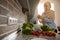 Charming Arab Muslim woman wipes her hands with a towel after washing vegetables in the kitchen. The sun s rays penetrate through