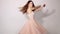 Charming and attractive young girl with chestnut hair, wearing trendy pastel pink dress. Adorable model twirling and