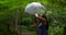 Charming beautiful woman twisting an umbrella in rainy day at beautiful park.