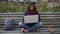 Charming biracial woman sitting on bench outdoors, working on laptop, freelancer