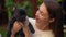 Charming black French Bulldog puppy licking face of young Caucasian woman in slow motion. Little purebred puppy enjoying