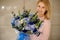 charming bouquet with blue roses in hands of young smiling woman